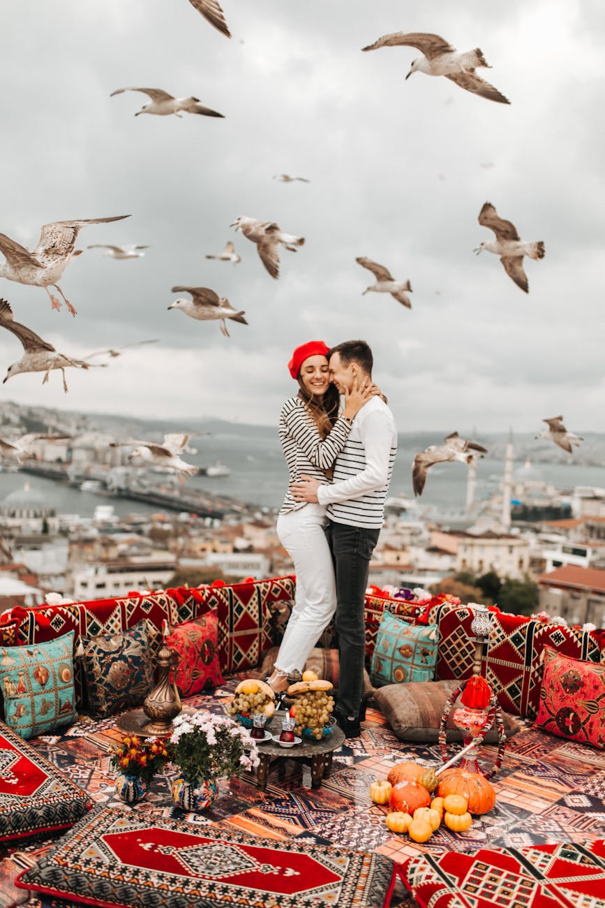 birds flying over a man and woman hugging each other face to face